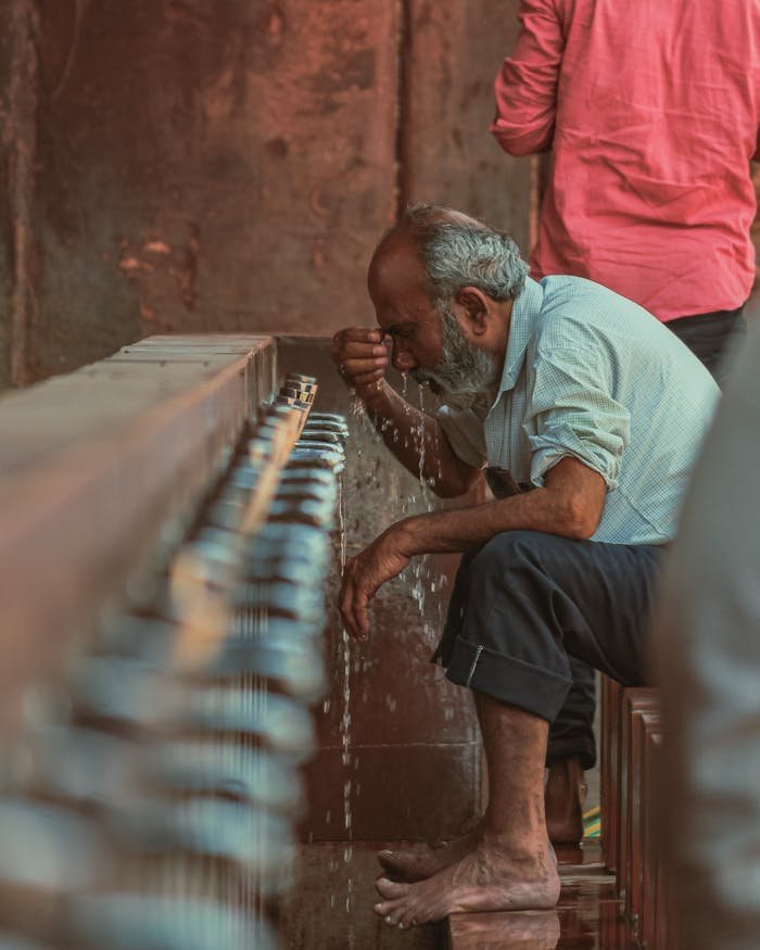 A candid shot of an elderly man washing his face at public water taps in New Delhi.